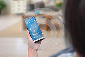 Woman use climate control app on a phone in the living room to adjust temperature and ventilation