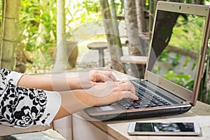 Woman use computer. With garden view background.