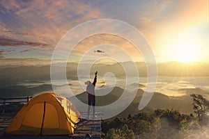 A woman use drone for take a photo landscape between sunrise and fog background at top of mountain at Tak photo