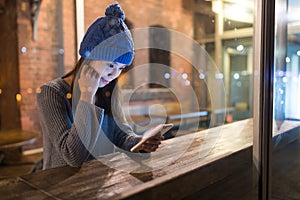 Woman use of mobile phone inside cafe at night