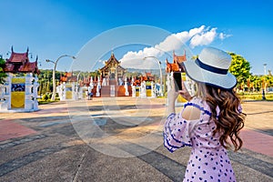 Woman use mobile phone take a photo at Ho kham luang northern thai style in Royal Flora ratchaphruek in Chiang Mai,Thailand. photo