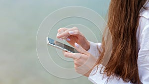 Woman use mobile phone to search in internet check app outside. Woman with long hair Closeup female hands with smartphone rest at