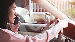 A woman use a mobilephone to talk while driving to ask for directions. The concept is unsafe to use a mobile phone while driving
