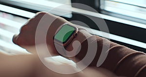 Woman use modern smartwatch with a green screen chromakey. Wearable technology device closeup. Mock-up for tracking.