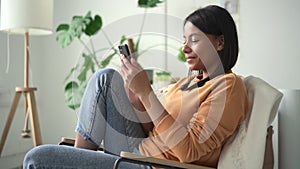 Woman use phone at home Spbd. 20s mixed race african female sit in modern white living room