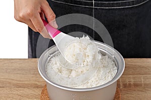 Woman use rice spoon to scoop rice from pot