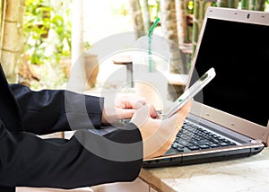 Woman use smart phone with computer. Garden view background.