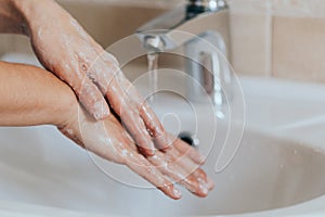 Woman use soap and washing hands under the water tap. Hygiene concept hand detail