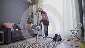 Woman use vacuum cleaner to cleaning the carpet in living room during daily clean.