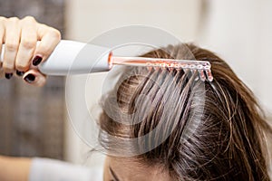 Woman uses darsonval for massage head& x27;s skin.