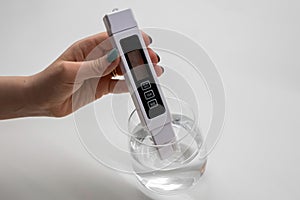 Woman uses a digital conductivity meter to check the purity of water
