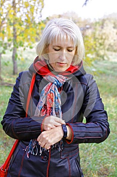 A woman uses a fitness bracelet while walking in the park