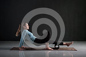 Woman uses foam roller to remove pain, stretch and massage muscles of legs.