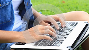 Woman uses laptop on grass in the park