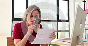 Woman uses magnifying glass to read information at work
