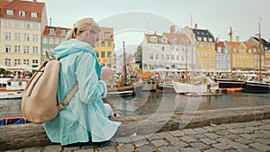 Woman uses smartphone on background Nyhavn canal, against the background of famous colorful houses.