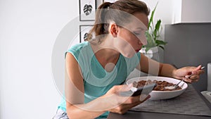 Woman uses a smartphone while eating her breakfast