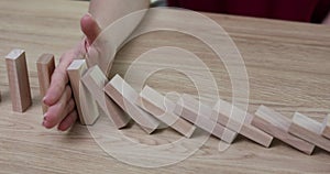 Woman uses wooden blocks to explain domino effect in office