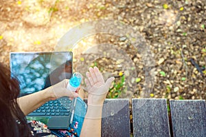 Woman using alcohol nano mist sprayer cleaning her hand before work with laptop to prevent the virus and bacterias. Quarantine for