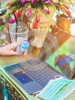 Woman using alcohol nano mist sprayer cleaning a laptop to prevent the virus and bacterias in her home. Quarantine for coronavirus photo