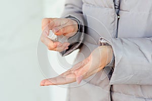 Woman using anti bacterial spray outdoors. Female hands applying alcohol spray against coronavirus, close up. Antiseptic, hygiene