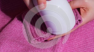 Woman using Anti-pilling razor at home. Device for shaving clothes. Anti-Plush fabric Shaver. Electric portable sweater