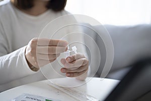 Woman using antigen test kit for testing COVID-19 test with ATK at home