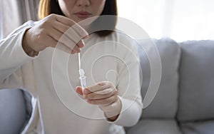 Woman using antigen test kit for testing COVID-19 test with ATK at home