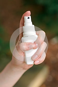 Woman using antiseptic spray outdoors