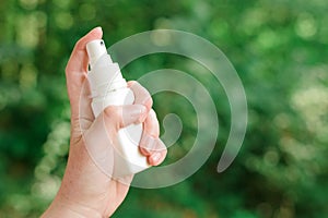 Woman using antiseptic spray outdoors