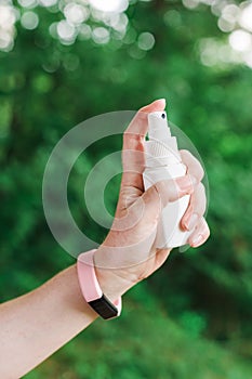 Woman using antiseptic spray outdoors