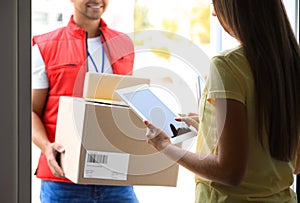 Woman using app to confirm delivery of parcels from courier on doorstep