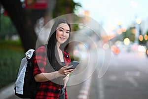 Woman using application of taxi service app on smart phone while standing on street.