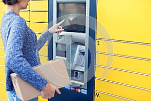 Woman using automated self service post terminal machine or lock