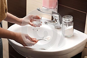 Woman using baking soda to unclog sink drain in bathroom, closeup