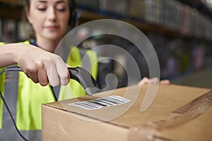 Woman using barcode reader on a box in a warehouse, detail photo