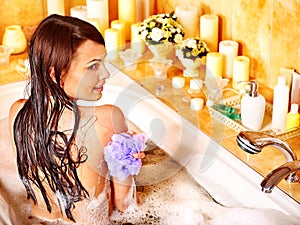 Woman using bath sponge in bathtub.