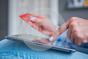 Woman using black tablet and red credit card for online shopping at bright room