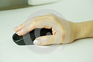 Woman using a black wireless computer mouse on white background. A woman's hand holds a computer mouse. Working with th