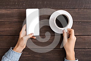 Woman using blank smartphone and drinking coffee