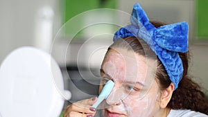 Woman using brush to apply moisture acne and pimple clay mask, moisture cream. Hygiene and dermatology, facial massage