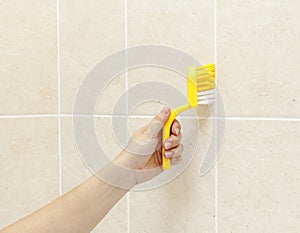Woman using brush to wash shower tiles