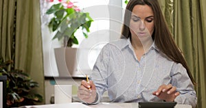 Woman using calculator for calculate domestic bills at home