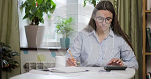 Woman using calculator for calculate domestic bills at home