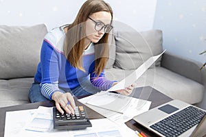 Woman using calculator for calculate domestic bills at home, doing paperwork for paying taxes