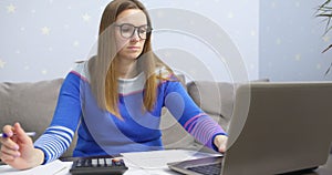 Woman using calculator for calculate domestic bills at home, doing paperwork for paying taxes