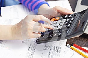 Woman using calculator for calculate domestic bills at home, doing paperwork for paying taxes