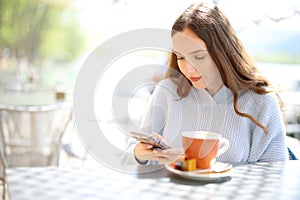 Woman using cell phone in a coffee shop terrace