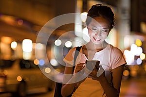 Woman using cellphone in the city at night