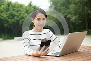 Woman using cellphone and laptop computer